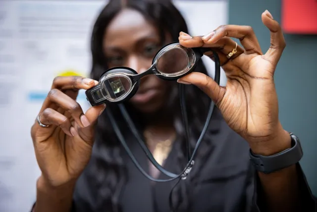 A woman holding up a pair of goggles.