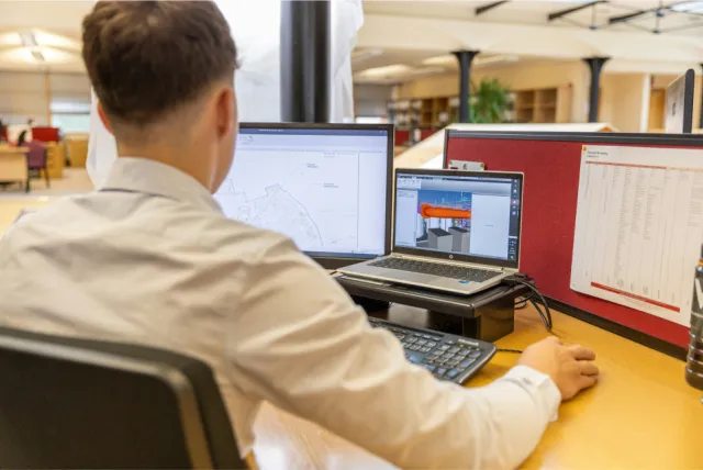 A person working at a desk with two monitors.