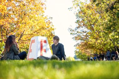 two people sitting in front of the UBC cairn.