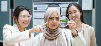 a student holding a medical sample, with 2 other students around her