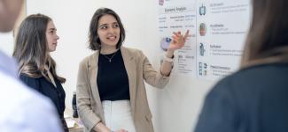 A woman enthusiastically presenting a detailed economic analysis poster.